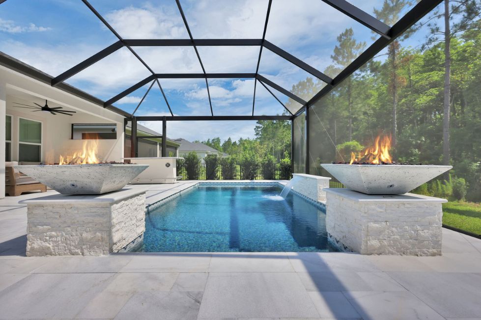 Modern rectangular pool with fire bowls inside a screened lanai