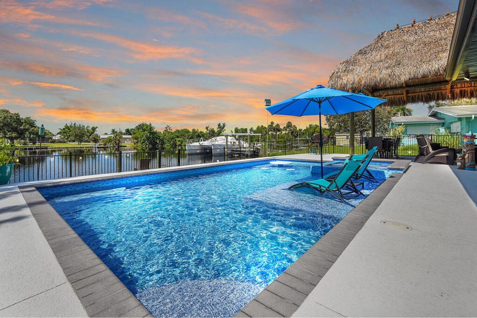 Luxury pool overlooking a lake with sun shelf seating and umbrella
