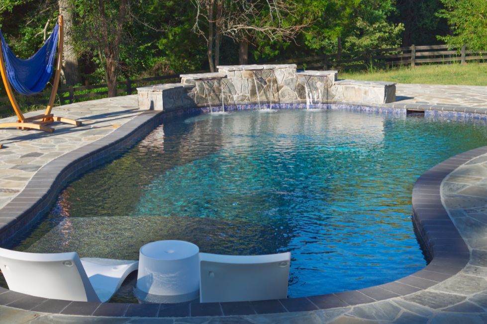 Freeform luxury backyard pool with waterfall feature and tanning ledge