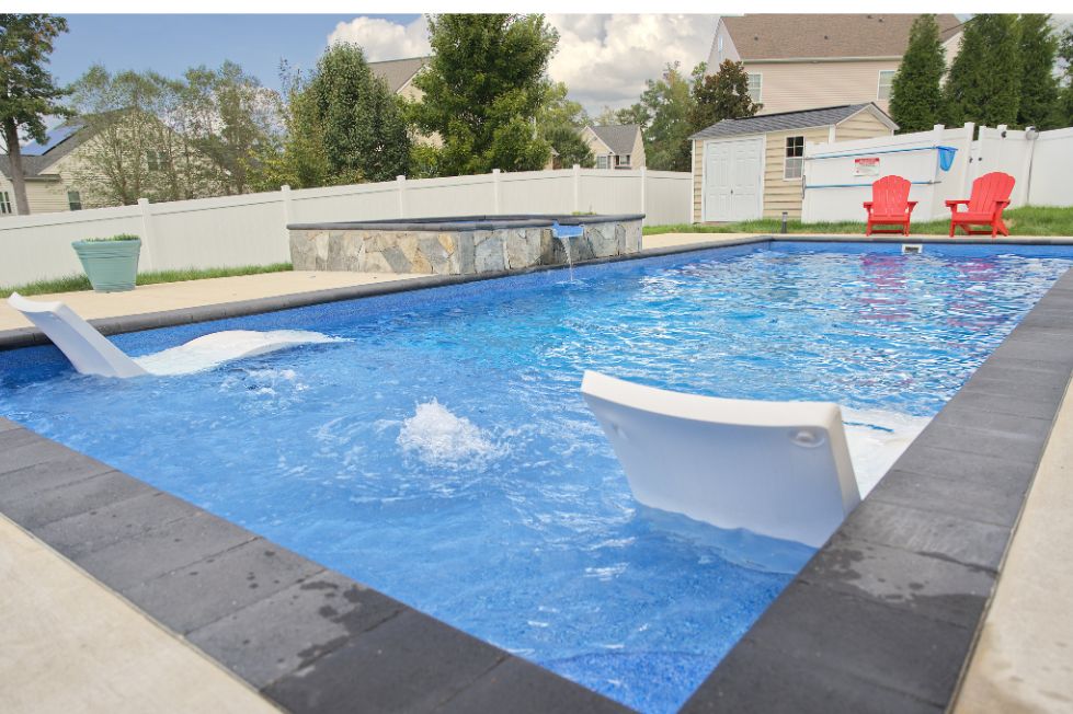 Rectangular backyard pool with tanning ledge loungers