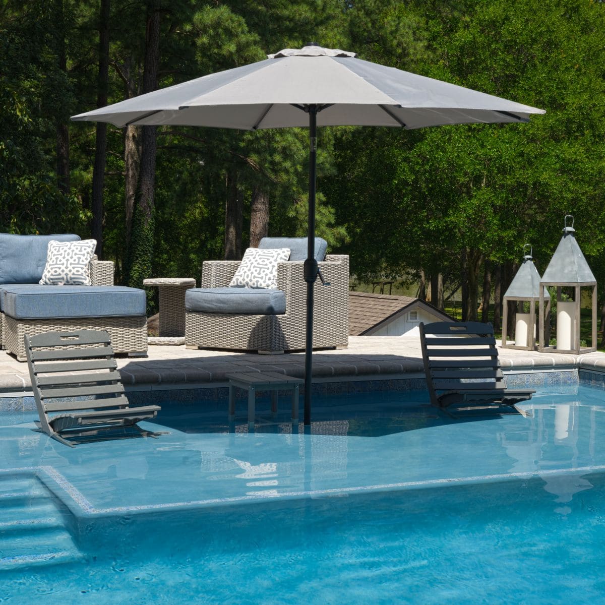 Pool tanning ledge with in-water loungers and umbrella