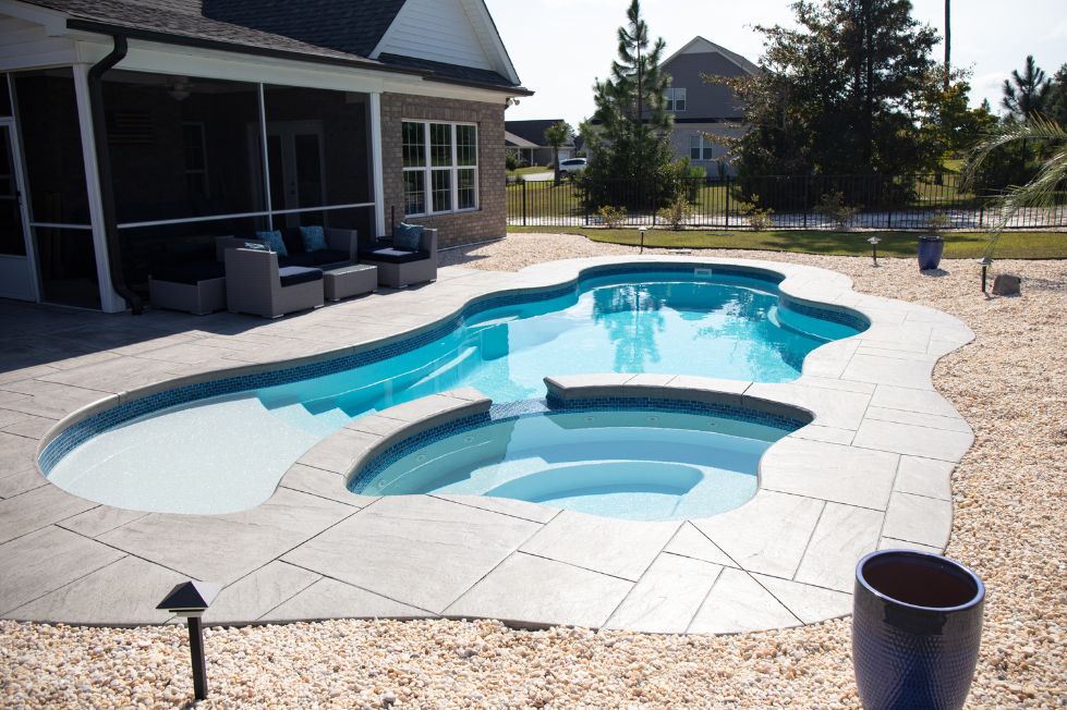 Freeform fiberglass pool with tanning ledge and spillover spa