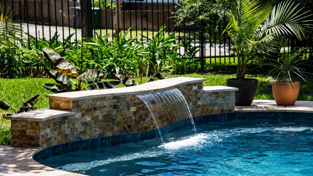 Swimming pool with a raised sheer descent waterfall and natural stone water feature
