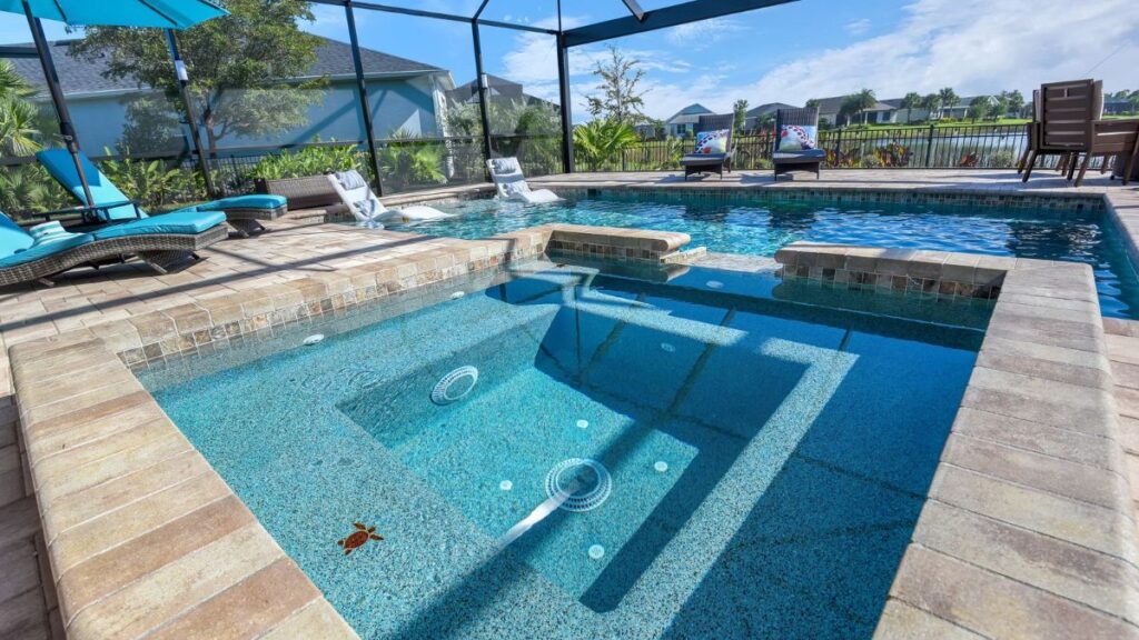 Inground pool with raised spa, poolside loungers, and screened enclosure