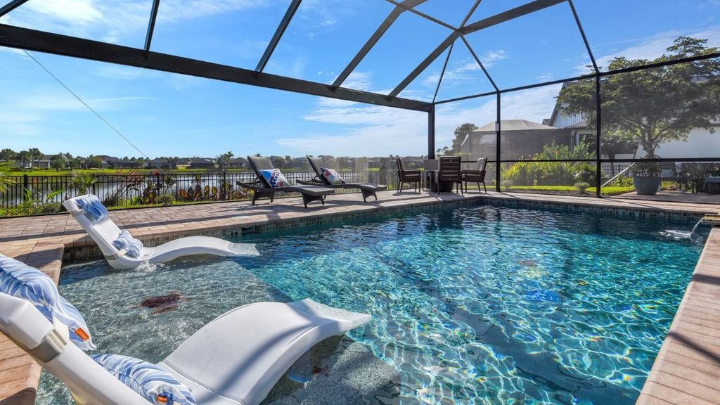 Inground pool with tanning ledge, in-pool loungers, and screened enclosure