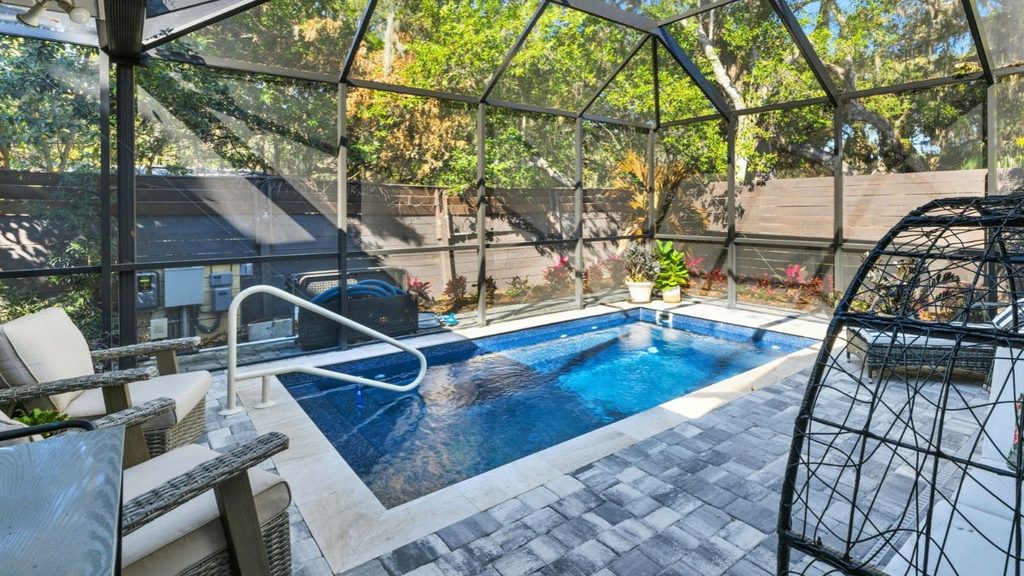 Inground pool with screened enclosure, paver patio, and poolside seating