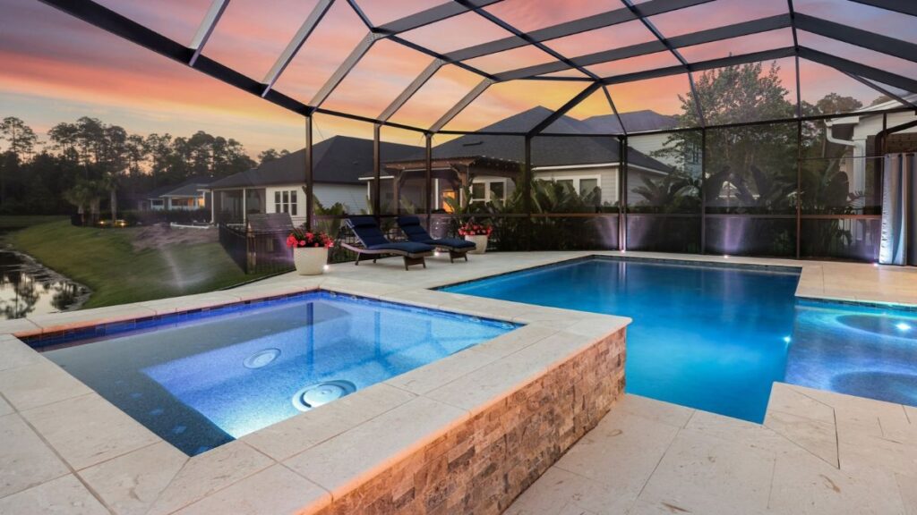 Inground pool and raised spa with screened enclosure at sunset